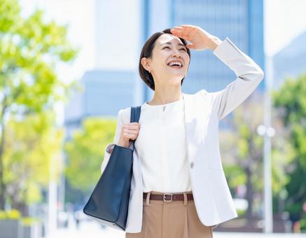 強い日差しの中営業に向かうOL 強い日差しの中営業に向かうOLの写真
