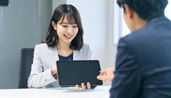タブレットを使って説明する女性営業マン タブレットを使って説明する女性営業マンの写真