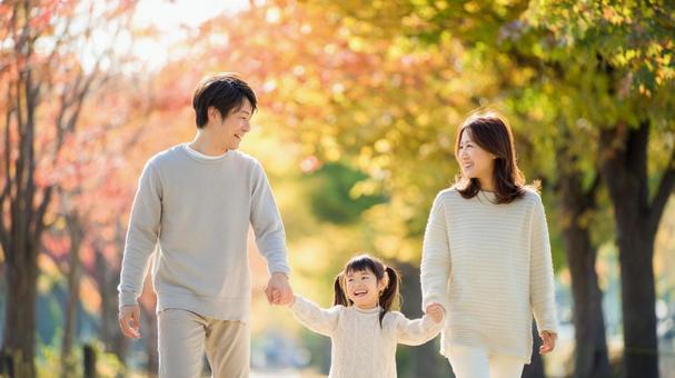 秋の並木道を歩く幸せそうな家族 秋の並木道を歩く幸せそうな家族の写真