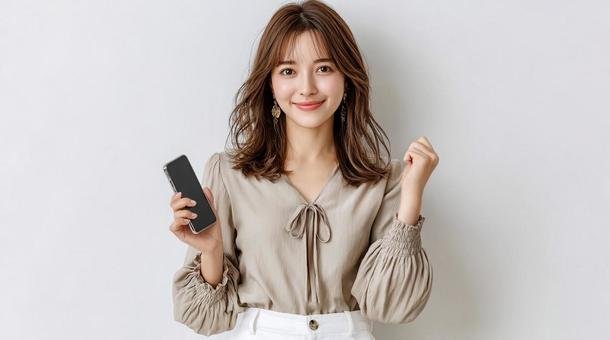 スマホを手に笑顔でガッツポーズする女性 スマホを手に笑顔でガッツポーズする女性の写真