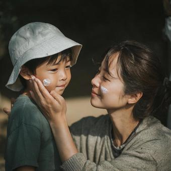 母親が息子に日焼け止めを塗るシーン 母親が息子に日焼け止めを塗るシーンの写真