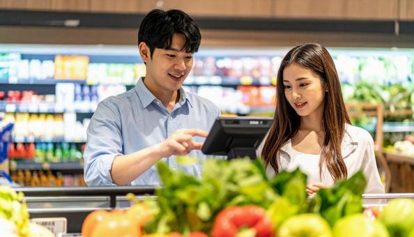 スーパーでセルフレジを使う若い日本人夫婦 スーパーでセルフレジを使う若い日本人夫婦の写真
