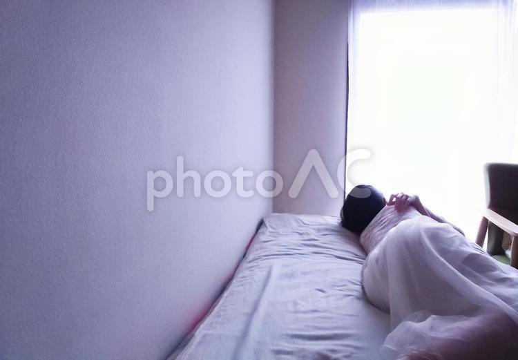 ベッドの上に寝そべる女性(横長) 女性,寝る,ベッドの写真素材