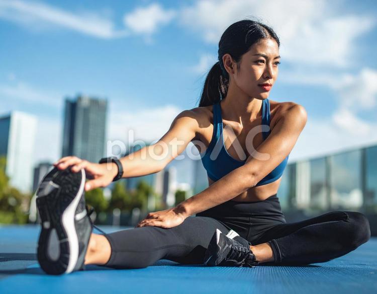 青空の下でのクールダウンする女性 ストレッチ,女性,スポーツウェアの写真素材