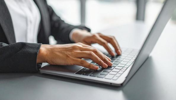 パソコンに両手で入力するデスクワークの写真