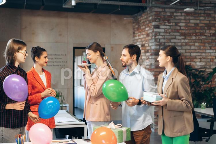 オフィスで誕生日ケーキの匂いを嗅ぐ女性 ビジネス,ビジネスマン,ビジネスウーマンの写真素材