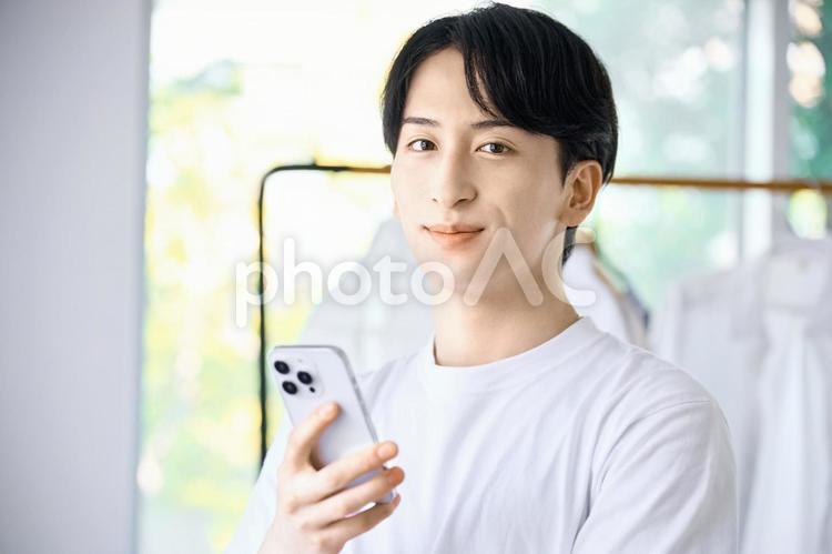 スマホを持つ若い男性　リビングルーム 男性,スマホ,一人暮らしの写真素材
