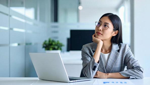 パソコンの前で悩む女性社員の写真