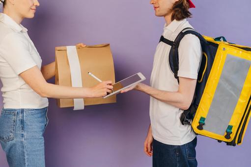 タブレットに受取サインを貰うフードデリバリーの男性 配達,フードデリバリー,デリバリーの写真素材