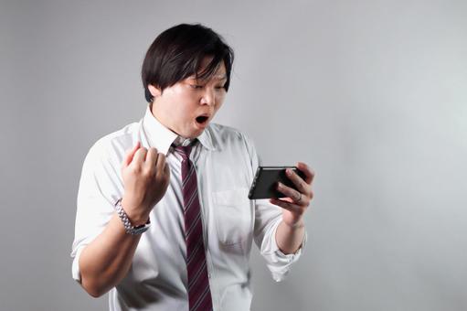 スマホを見て喜ぶ男性 スマホを見て喜ぶ男性 スマートフォン,男性,喜びの写真素材