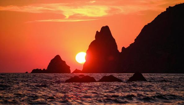 海の見える岩礁に沈む夕日 海の見える岩礁に沈む夕日の写真