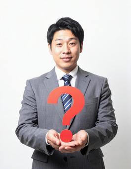 クエスチョンマークのオブジェを持つ男性 クエスチョンマークのオブジェを持つ男性の写真