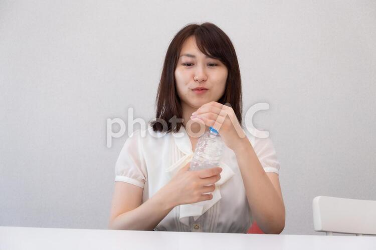 ペットボトルのキャップを開けようとしている女性 女性,ol,水分の写真素材