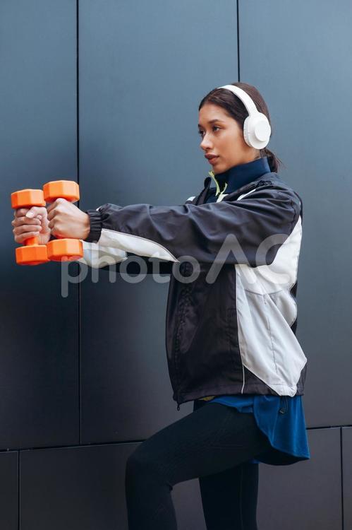 ダンベルを持って両手を突き出す女性 女性,ヘッドフォン,人物の写真素材