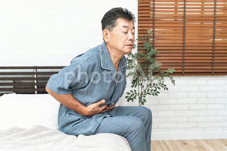 寝室で体調を崩す高齢者男性（腹痛） 腹痛,高齢者,お腹の写真素材