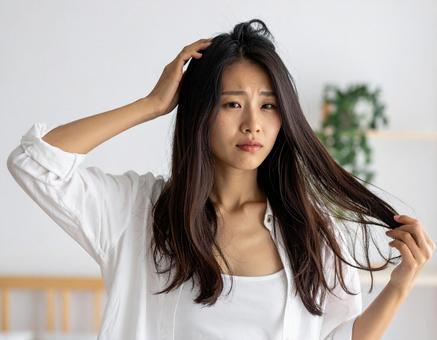 湿気で広がる髪に悩む女性 湿気で広がる髪に悩む女性の写真