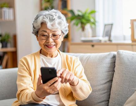 自宅のリビングでスマホを操作する女性 自宅のリビングでスマホを操作する女性の写真
