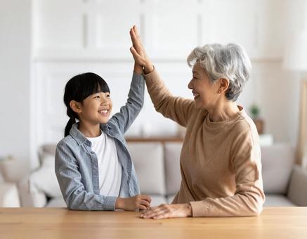 ハイタッチするおばあちゃんと孫の写真