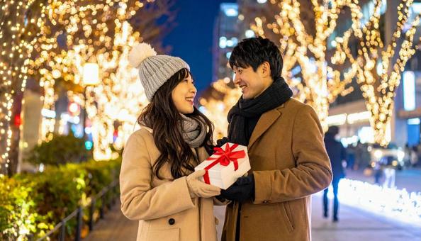 ギフトを手にする男女とイルミネーション ギフトを手にする男女とイルミネーションの写真