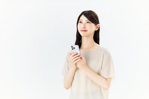 スマートフォンを持ち、見上げる女性 女性,スマホ,スマートフォンの写真素材