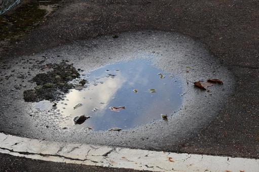 アスファルトの水溜りに青空と雲の映る風景 アスファルト,水溜り,青空の写真素材