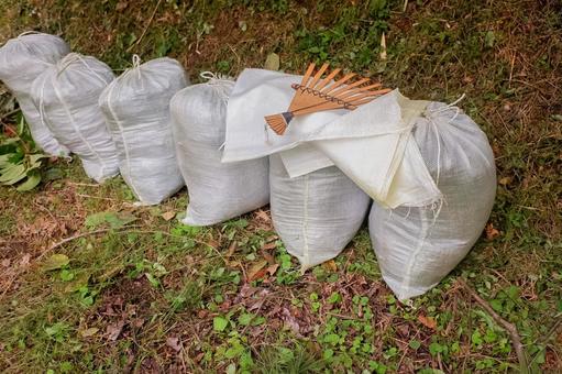 草刈り後　土嚢袋に集める 土嚢袋,袋,熊手の写真素材