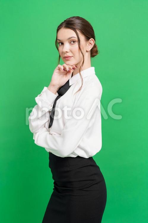 顎に手を当てポーズする女性（緑背景） 女性,考える,悩むの写真素材