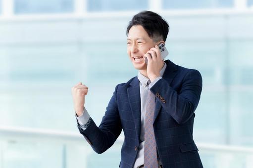 スマホで話しながらガッツポーズをする男性 男性,スマホ,笑顔の写真素材