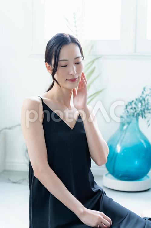 肌に触れる黒いワンピースを着た女性 ビューティー,女性,日焼け止めの写真素材