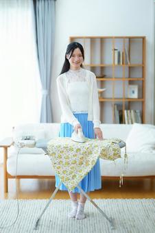 リビングでアイロンを掛けている女性 女性,アイロン,アイロン台の写真素材