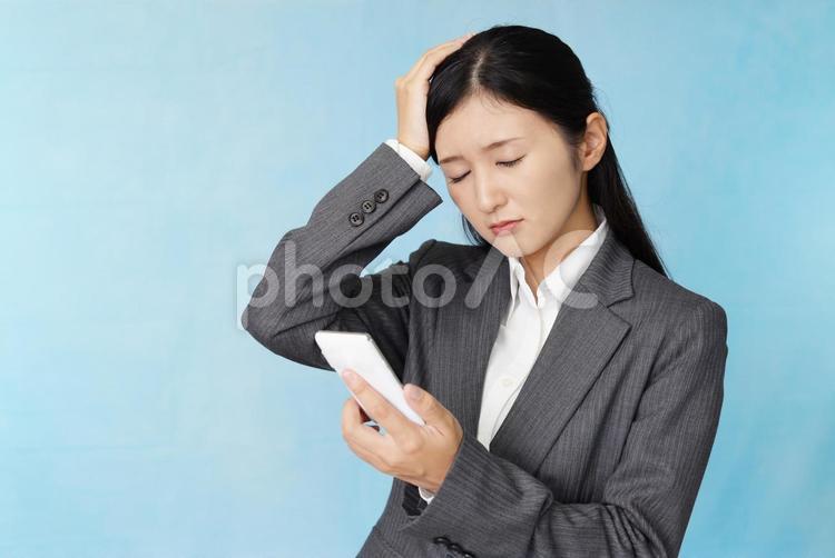 スマートフォンを持って頭を抱える女性 女性,スマホ,スマートフォンの写真素材