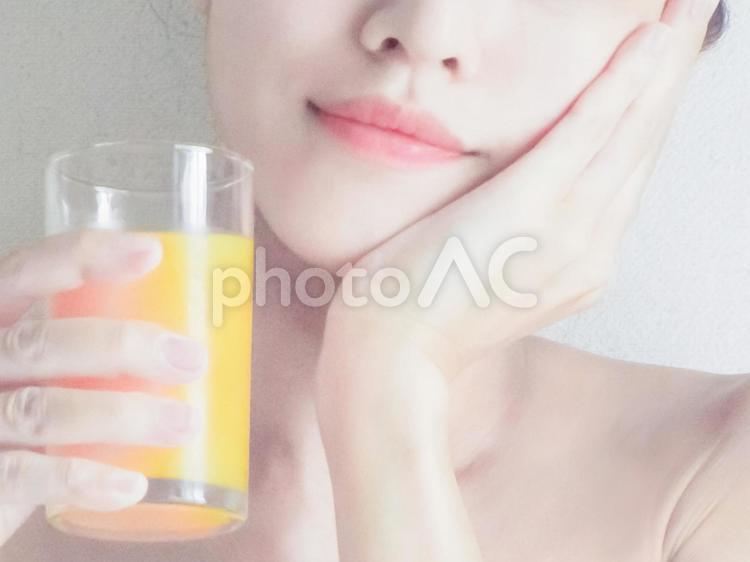 ジュースを持って頰を撫でる女性 女性,スキンケア,手の写真素材