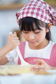 お菓子作りに集中するピンクのエプロン姿の少女 女の子,小学生,日本人の写真素材