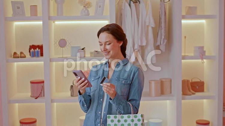 笑顔でスマートフォンを見る女性 女性,ショッピング,買い物の写真素材