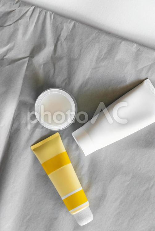 グレーの薄葉紙の上に置かれたチューブとクリームジャー モックアップ,物撮り,化粧品の写真素材