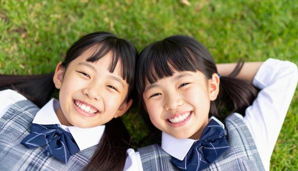 芝生に寝っ転がって笑顔の日本人姉妹 芝生に寝っ転がって笑顔の日本人姉妹の写真