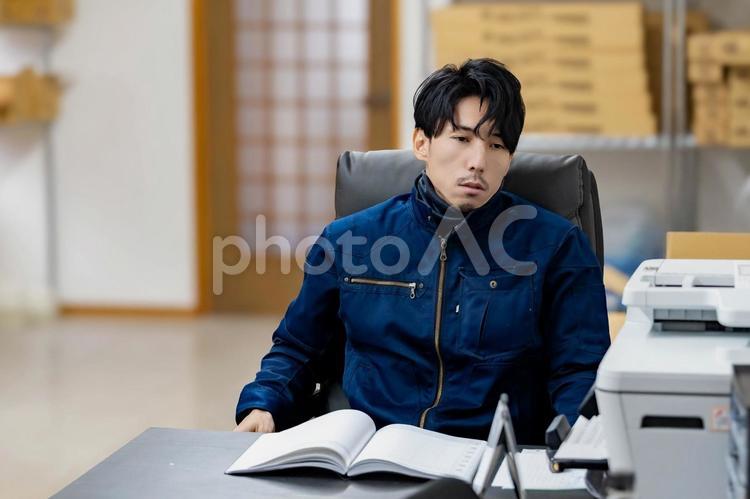 事務作業をする作業着姿の男性 ビジネス,ビジネスマン,男の写真素材