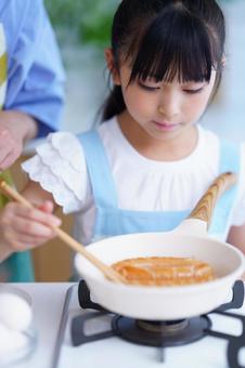 ソーセージを転がして焼く女の子のクッキングシーンの写真