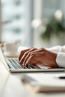 ノートパソコンでタイピングする手元の写真