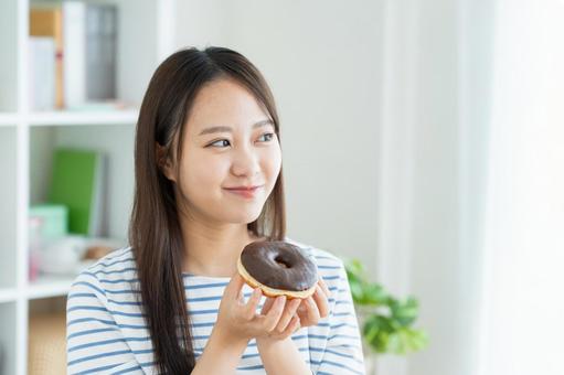 ドーナツを食べる若い女性 ドーナツを食べる若い女性 ドーナツ,スイーツ,ダイエットの写真素材