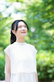 白いノースリーブワンピースの女性が立って見上げる 女性,見上げる,微笑むの写真素材