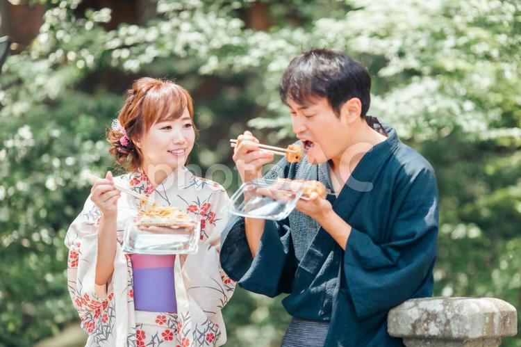 夏祭りにきて焼きそばやたこ焼きを食べる男女 浴衣,夏祭り,夫婦の写真素材