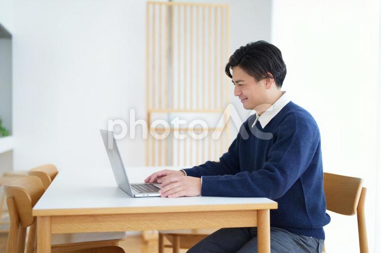 座って在宅ワークする男性 男性,パソコン,微笑むの写真素材