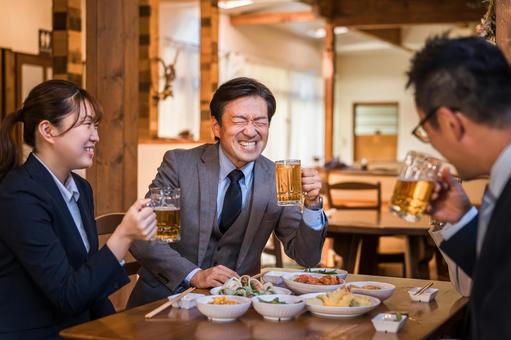 居酒屋で飲み会・宴会をする同僚の男女 居酒屋で飲み会・宴会をする同僚の男女 飲み会,飲みニケーション,懇親会の写真素材