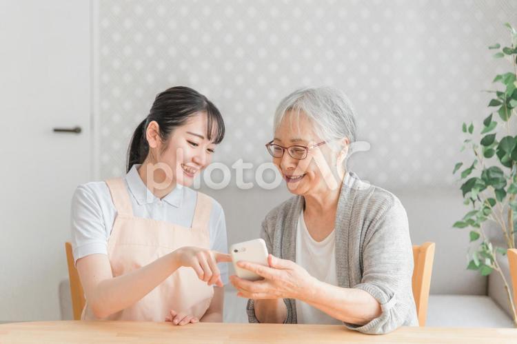 スマホを使う高齢者と女性スタッフ 高齢者,スマホ,スマートフォンの写真素材