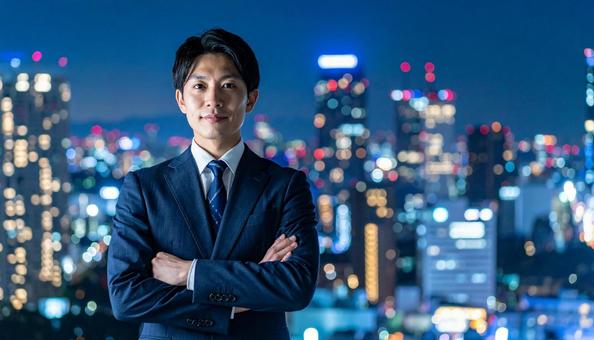 都市の夜景を背景に佇むビジネスマン 都市の夜景を背景に佇むビジネスマンの写真