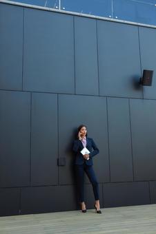 オフィスビルの黒い壁の前で電話するアジア人ビジネスウーマン ビジネスウーマン,ビジネス,女性の写真素材