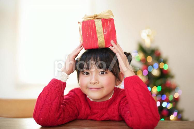 頭の上でプレゼントを持つ女の子 女の子,プレゼント,リボンの写真素材