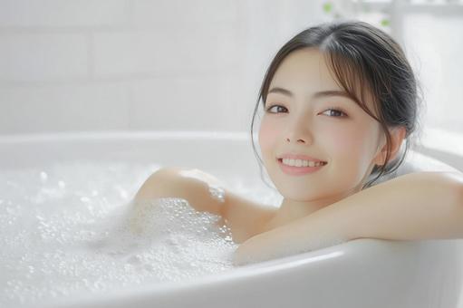 笑顔でバスタブの泡風呂に浸かる若い女性 笑顔でバスタブの泡風呂に浸かる若い女性の写真