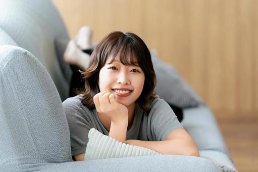 ソファに寝転ぶ笑顔の女性 ソファに寝転ぶ笑顔の女性 女性,ソファ,笑顔の写真素材